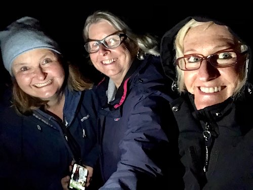 Drei Damen in der Nacht beim Warten auf Polarlichter
