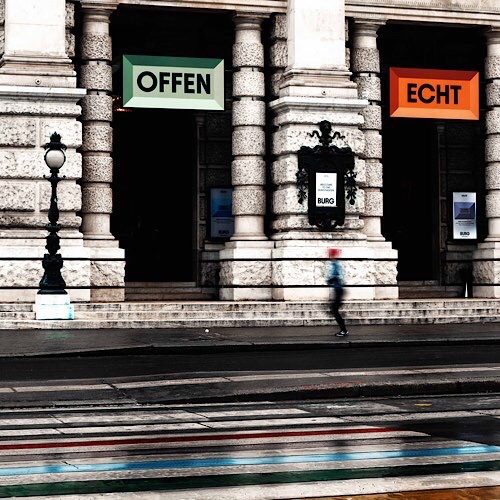 Bild vom Burgtheater Wien mit Läuferin in Bewegung, zwei Tafeln mit Aufschrift OFFEN und ECHT